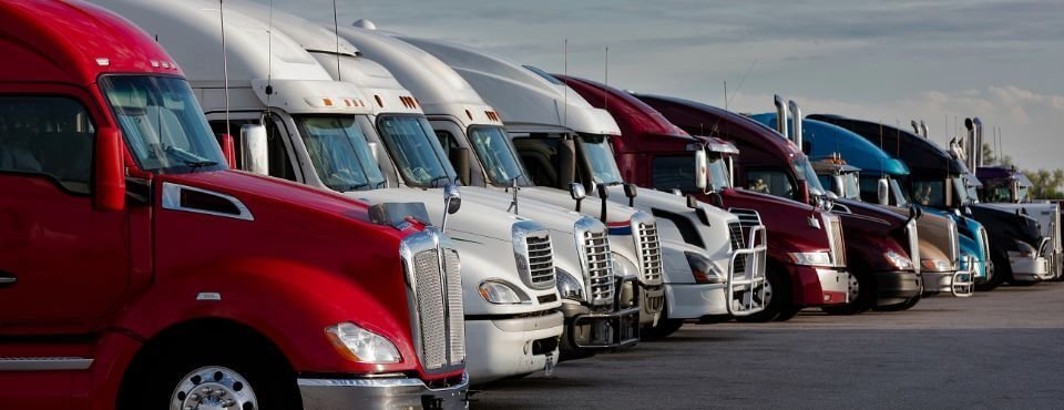 Junk removal truck options: a row of parked semi trucks led by a red cab