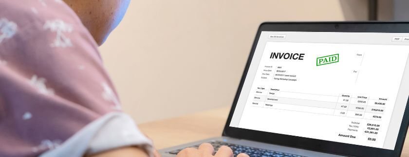 Junk removal cost calculator: person reviewing a paid junk removal invoice on a laptop
