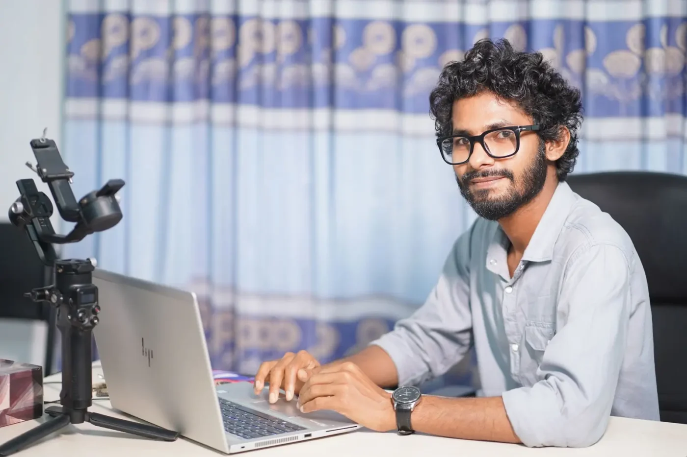 Website design services: web designer smiling while working on his laptop in a studio