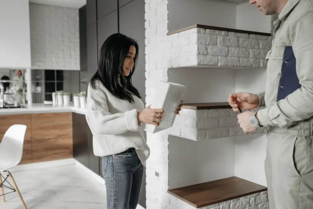 Homeowner holding a tablet while talking with a service technician in her kitchen Local Services Ads management: homeowner holding a tablet while talking with a service technician in her kitchen