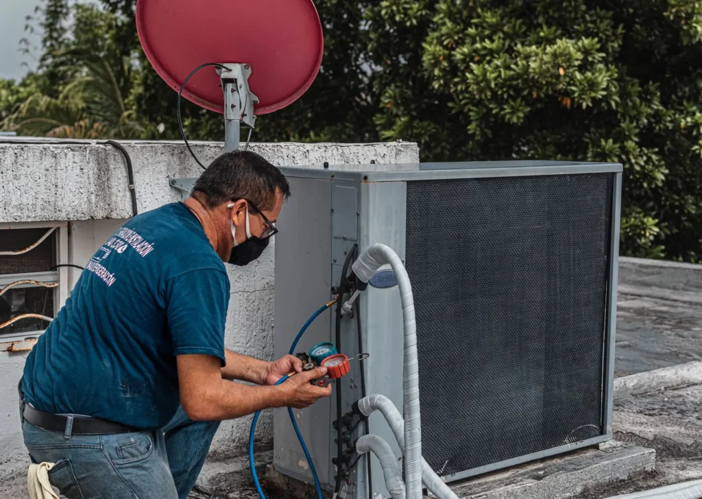 HVAC technician checking a rooftop air conditioning unit with refrigerant gauges HVAC marketing: HVAC technician checking a rooftop air conditioning unit with refrigerant gauges