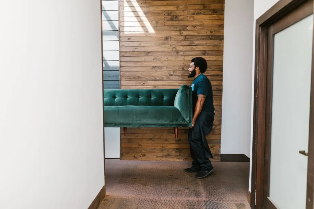 Mover carrying a green sofa through a doorway Moving company marketing: mover carrying a green sofa through a doorway