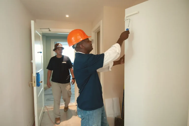 Home services marketing: painter in a hard hat rolling paint onto an interior wall while a coworker walks in