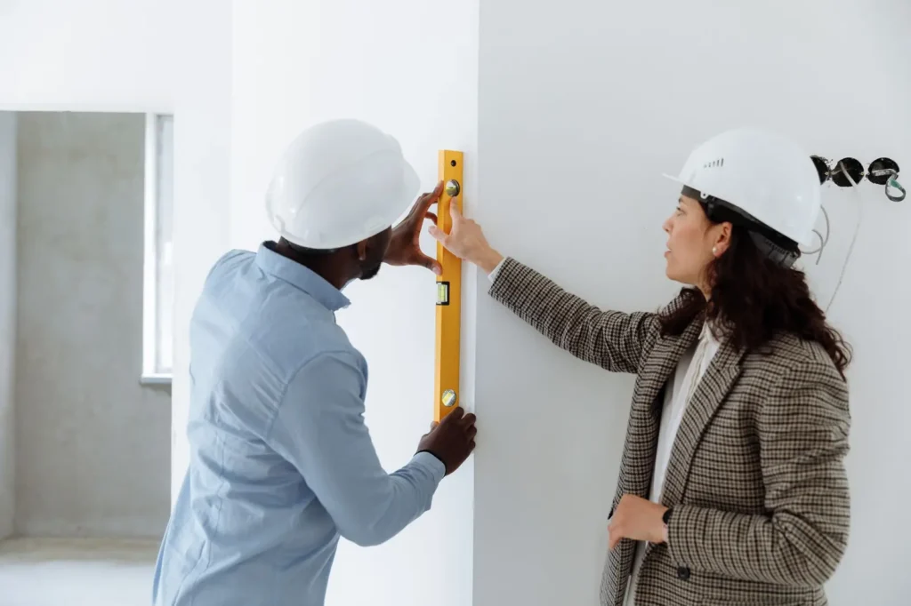 Remodeling marketing: contractors in hard hats checking a wall with a spirit level